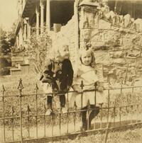 Two small children in front of house