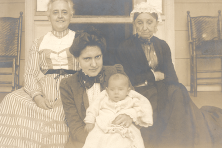 Photograph of three women sitting on a porch, one of whom holding a baby