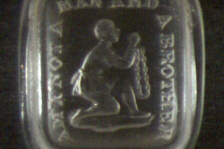 Metal button embossed with a slave kneeling in chains and the text "Am I not a man and a brother"